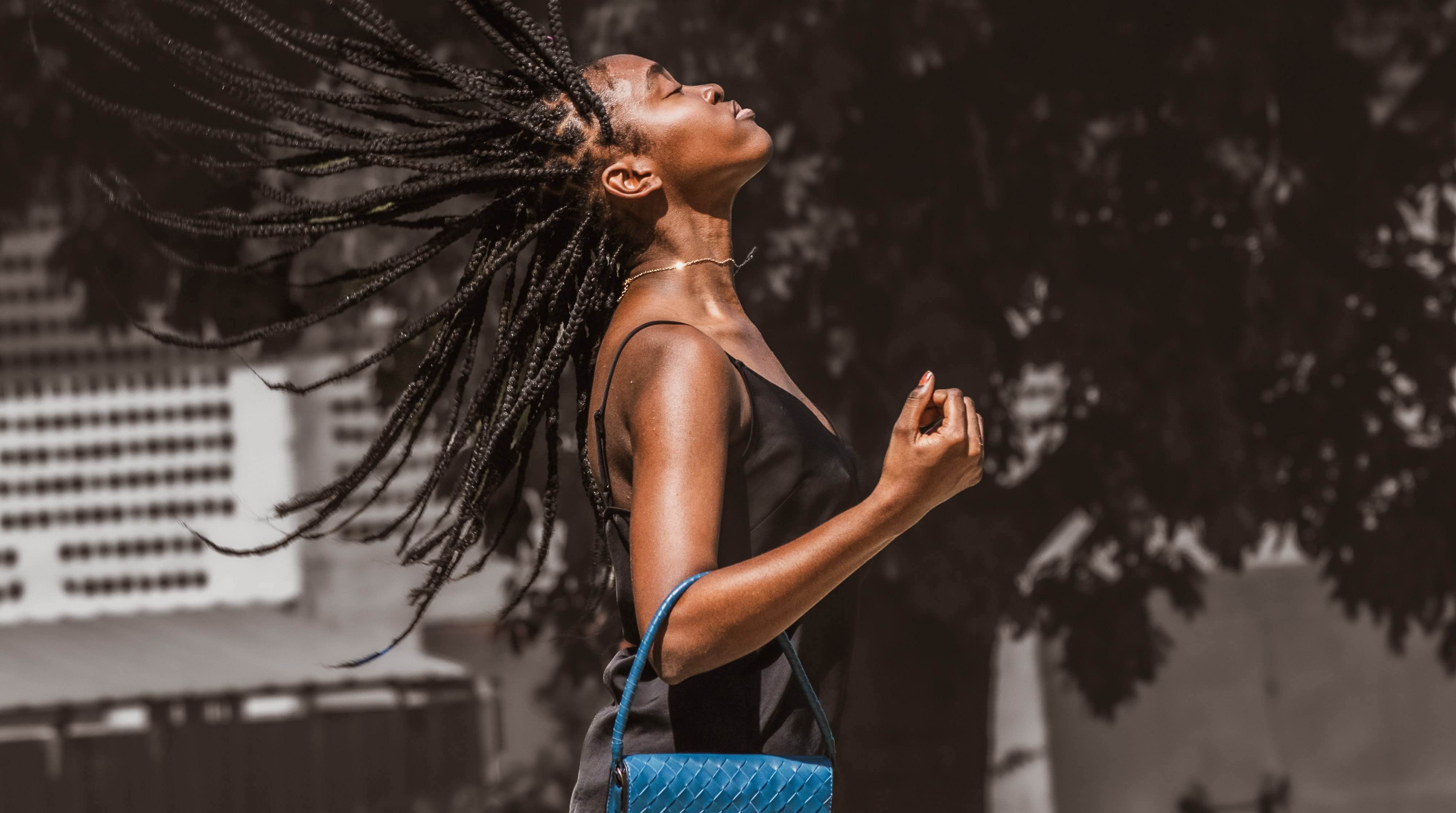 a women flipping her hair back and holding the blue crossbody bag.