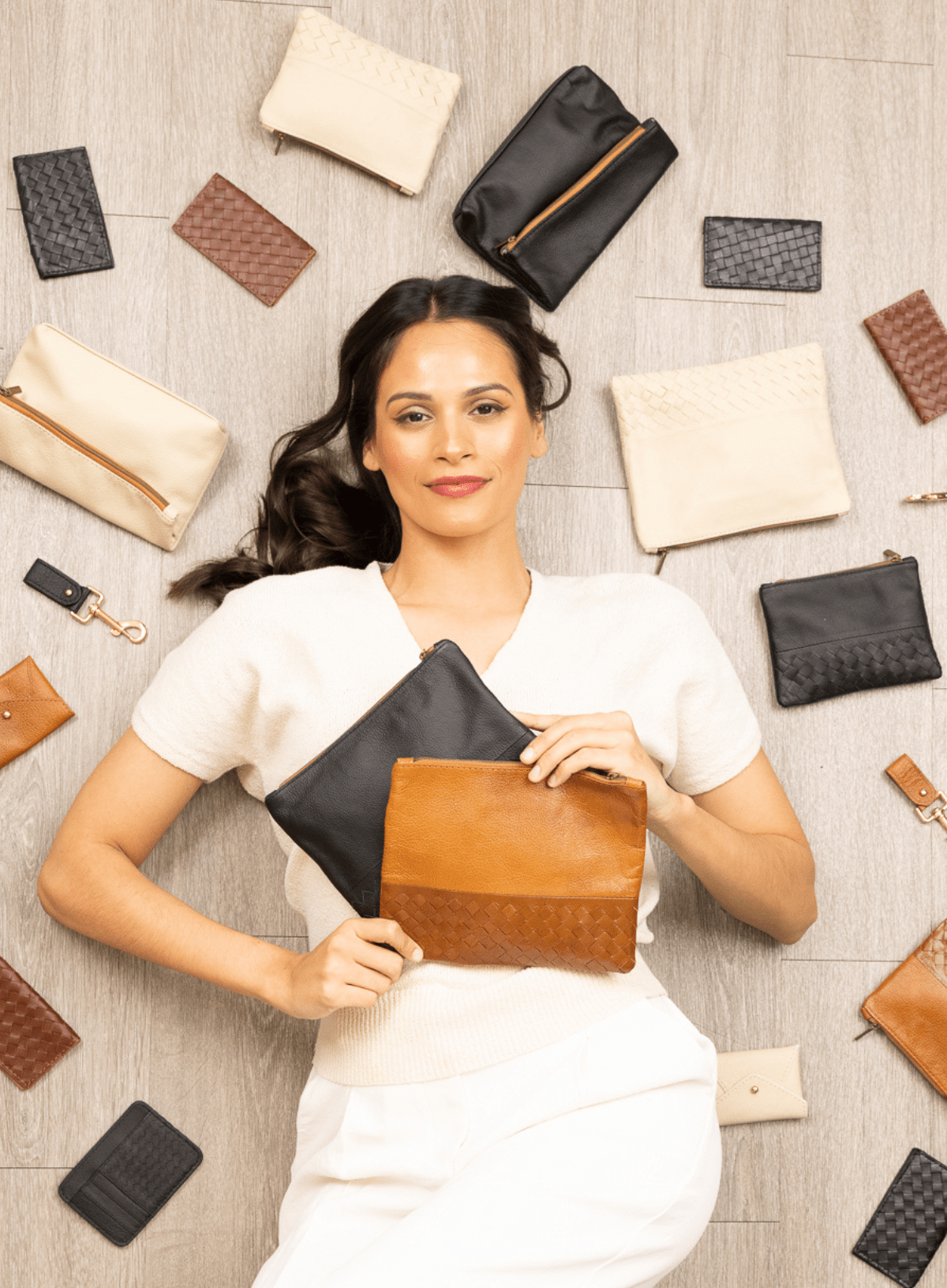 Woman holding leather pouches surrounded by various accessories