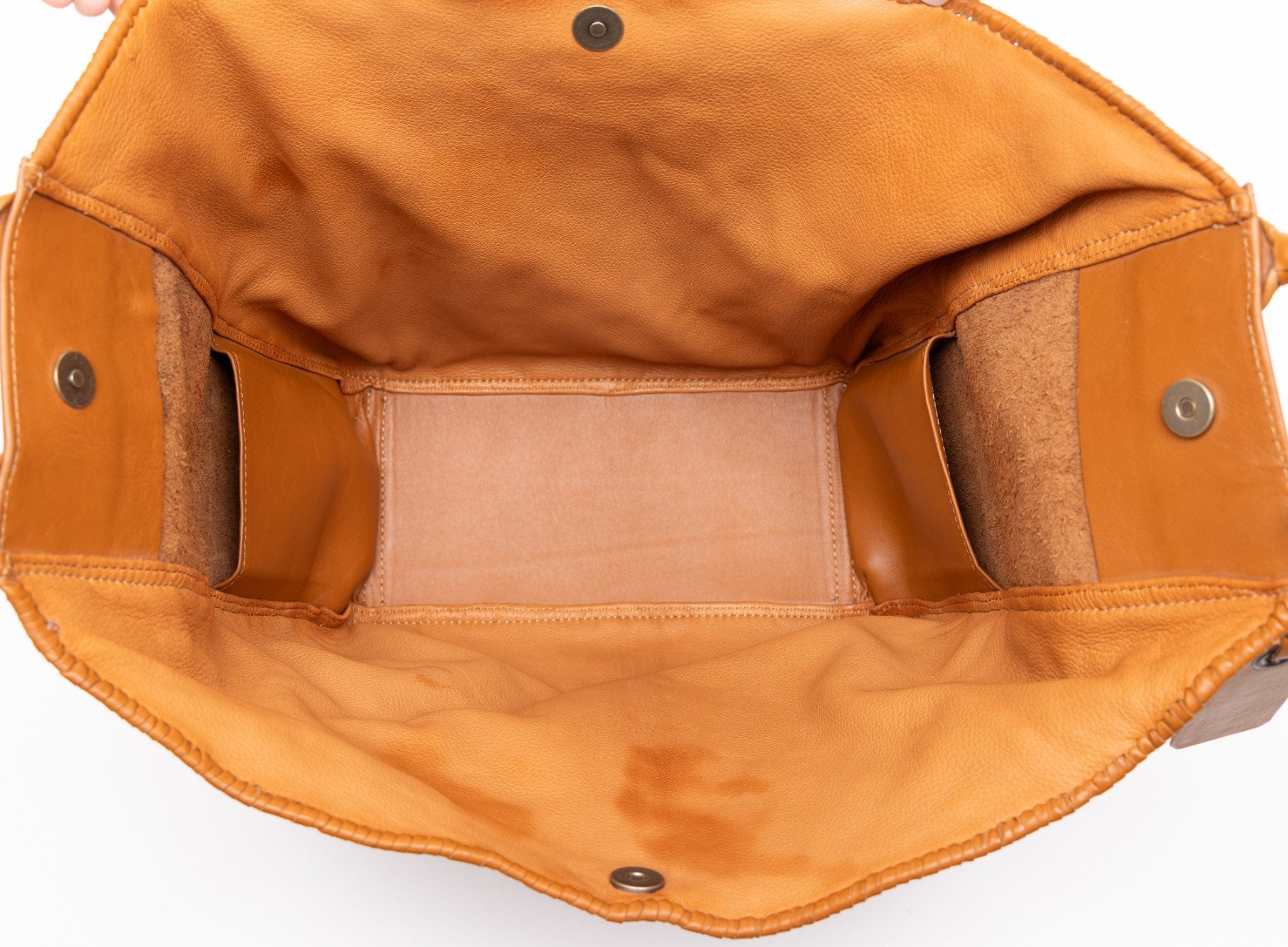 Close-up of a two-tone-camel leather bag with visible stitching and hardware on a white background