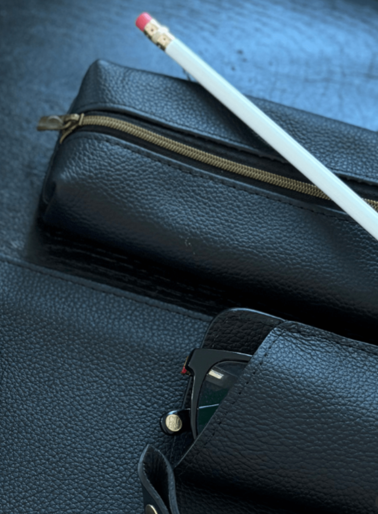 Black leather pencil case with pencil and glasses