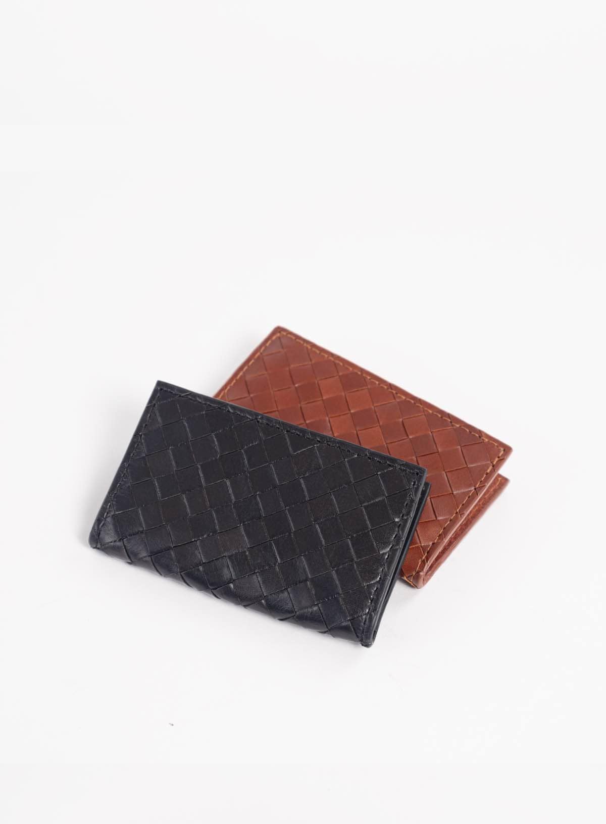 Black and brown woven leather wallets on a white background