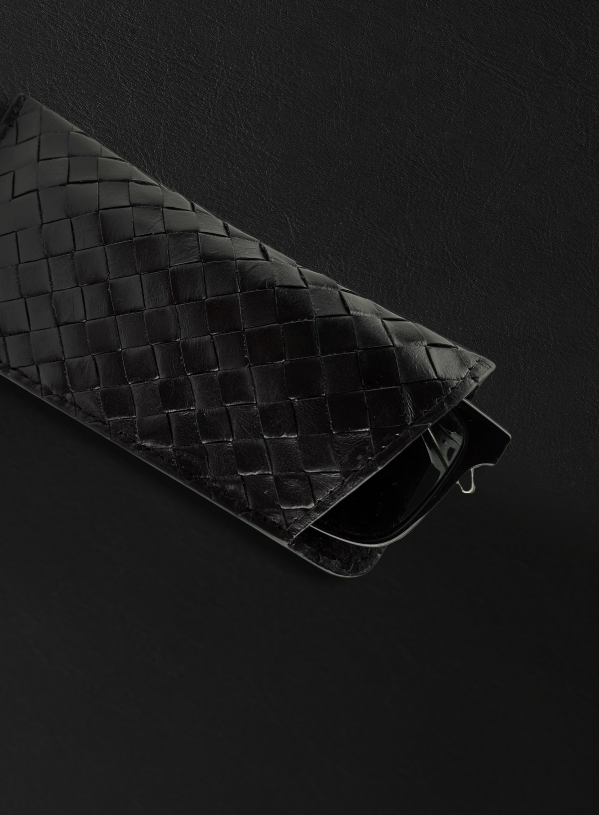 Black woven glasses case close-up on black surface