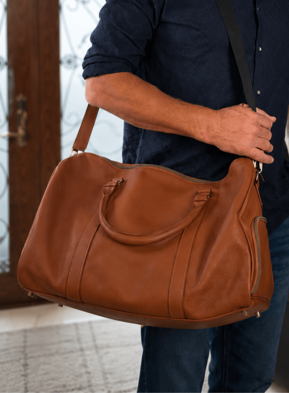 Person holding a brown leather bag indoors