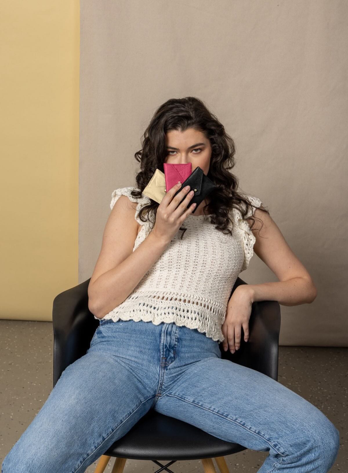 Woman sitting on a chair holding coin poucheswith a neutral background
