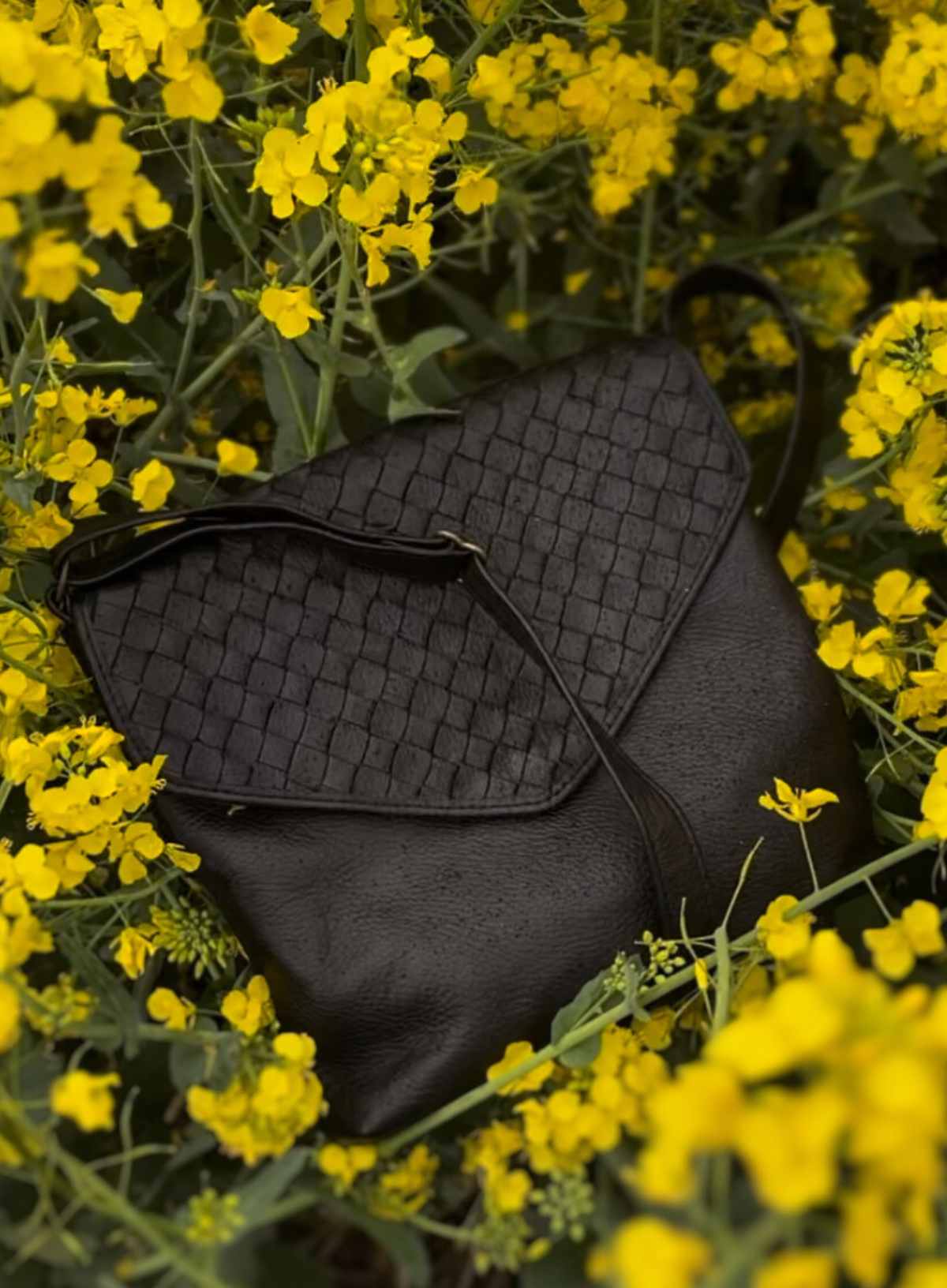 Black textured handbag on a bed of yellow flowers