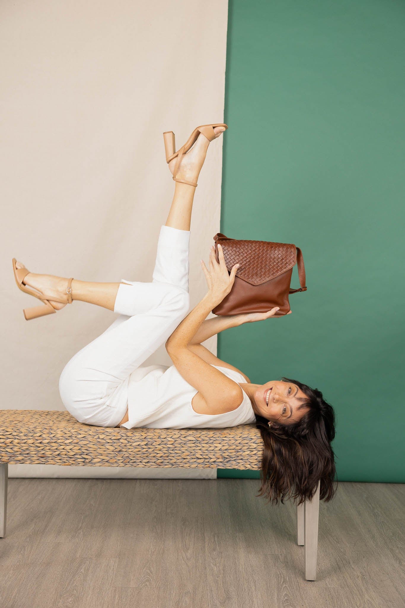 Envelope crossbody brown bag in front of white and green background