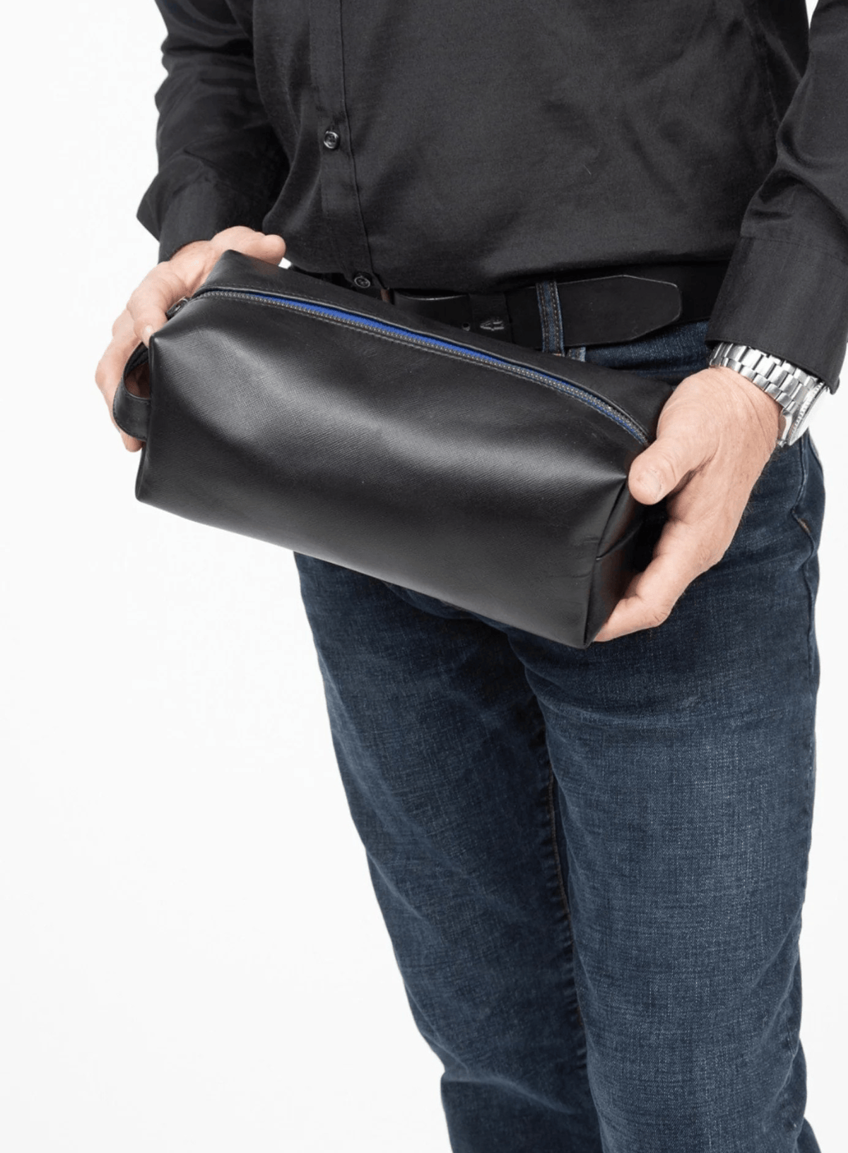 Person holding a black leather toiletry bag on a white background
