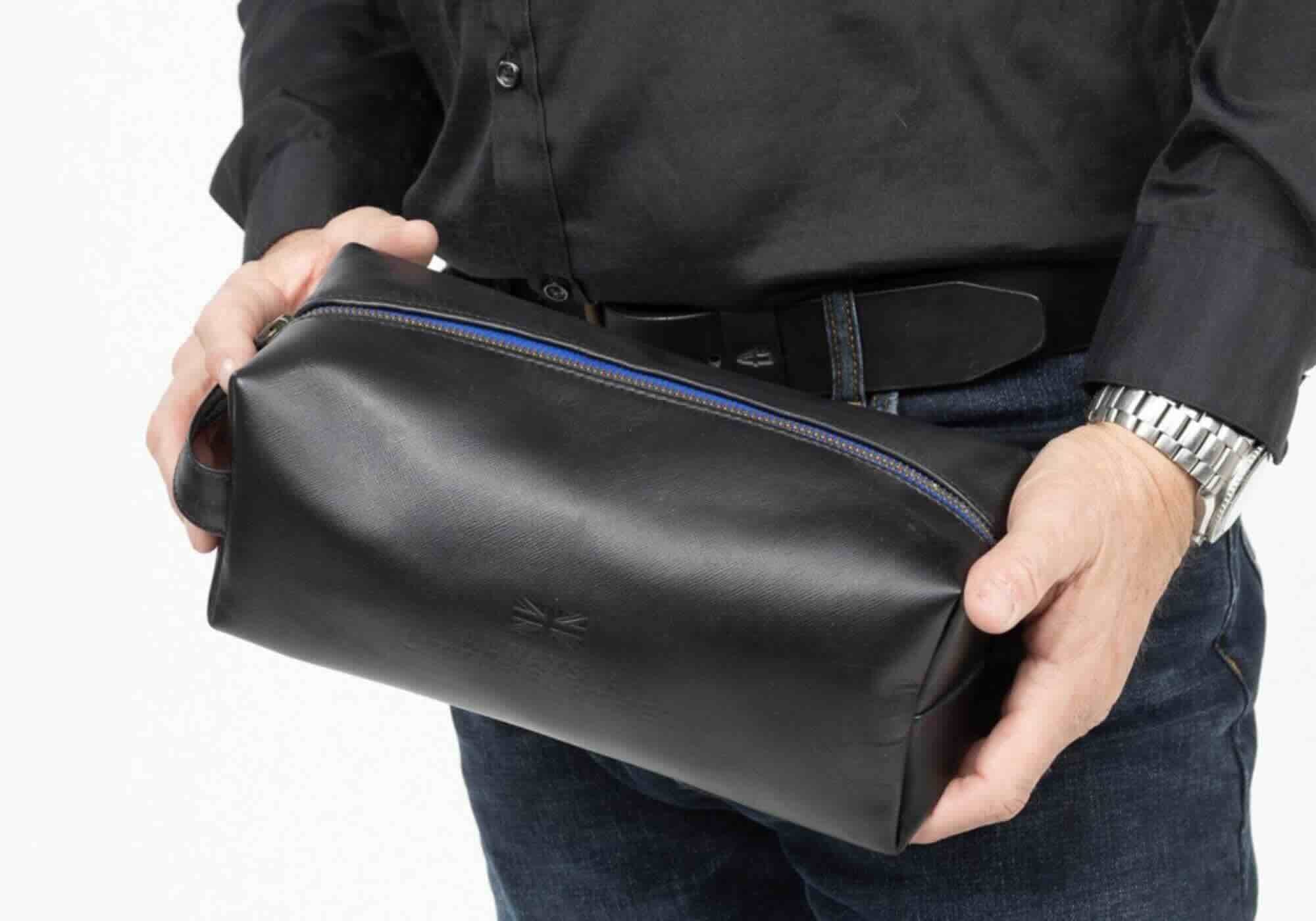Man holding black leather toiletry bag, close-up