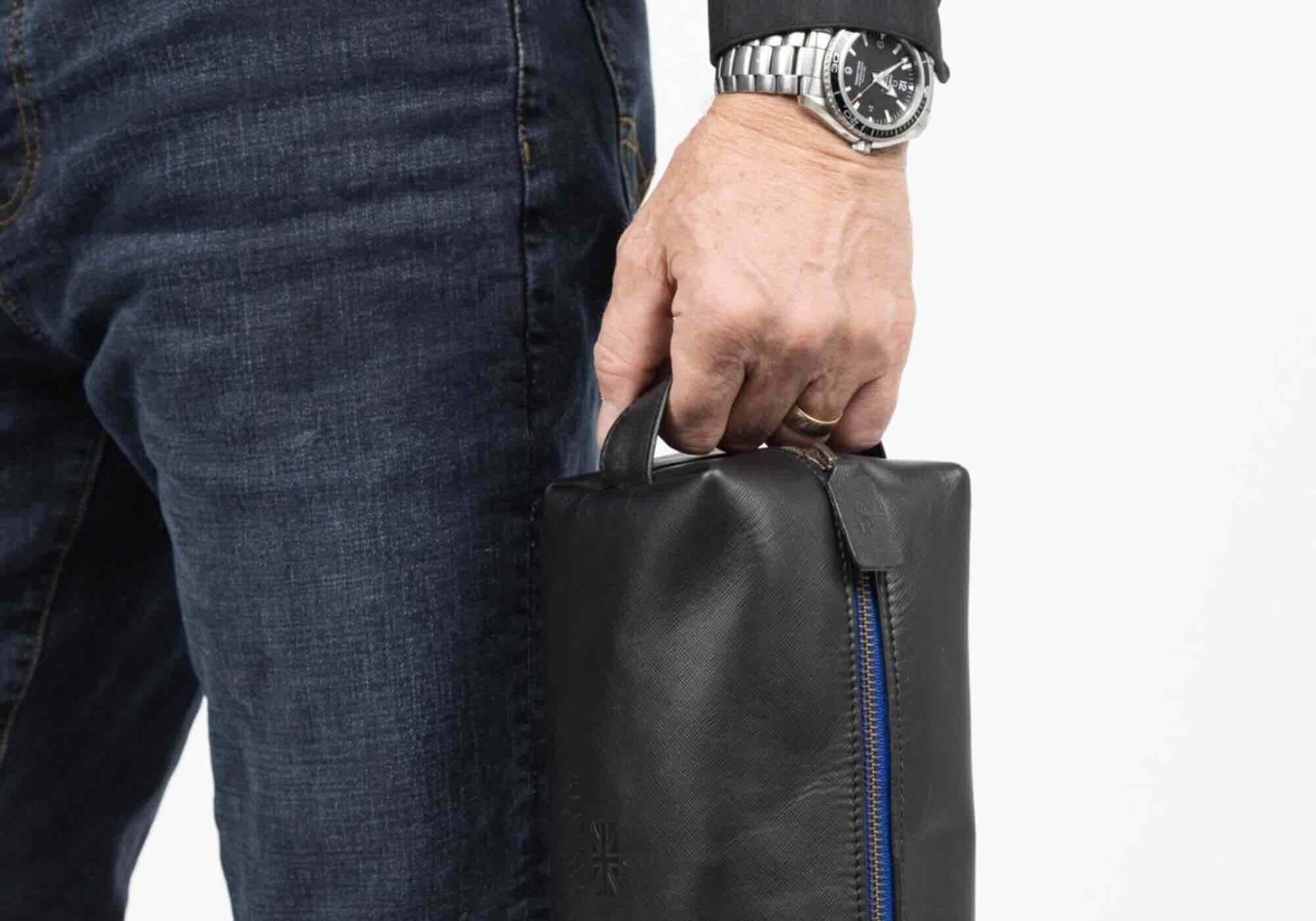Man holding iron-tight black toiletry bag