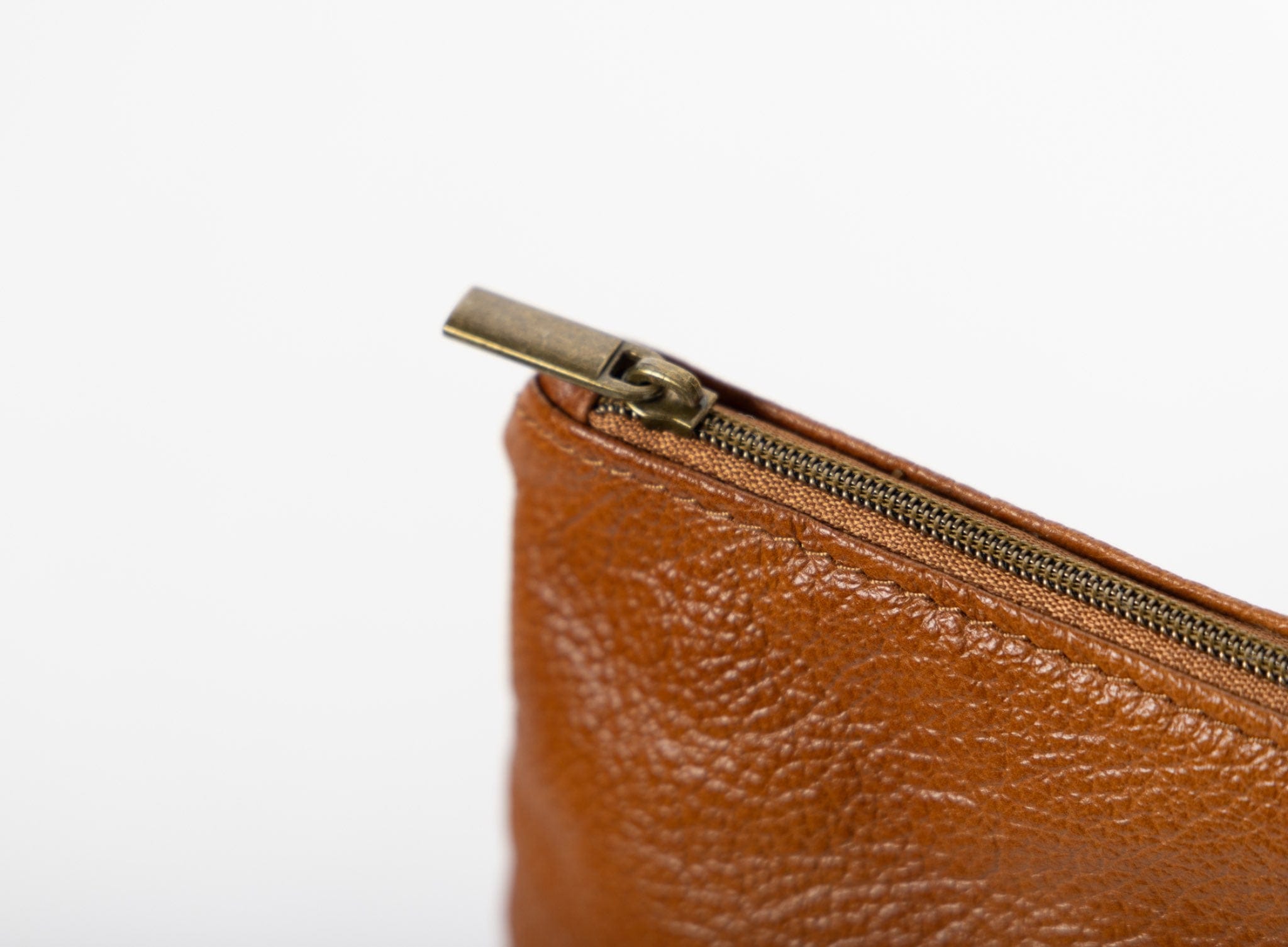 Cognac leather pouch with a zipper detail on a white background