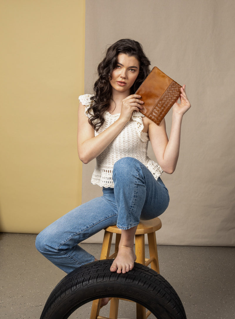 large pouch from ethically crafted accessories in cognac held by model showcasing front view.