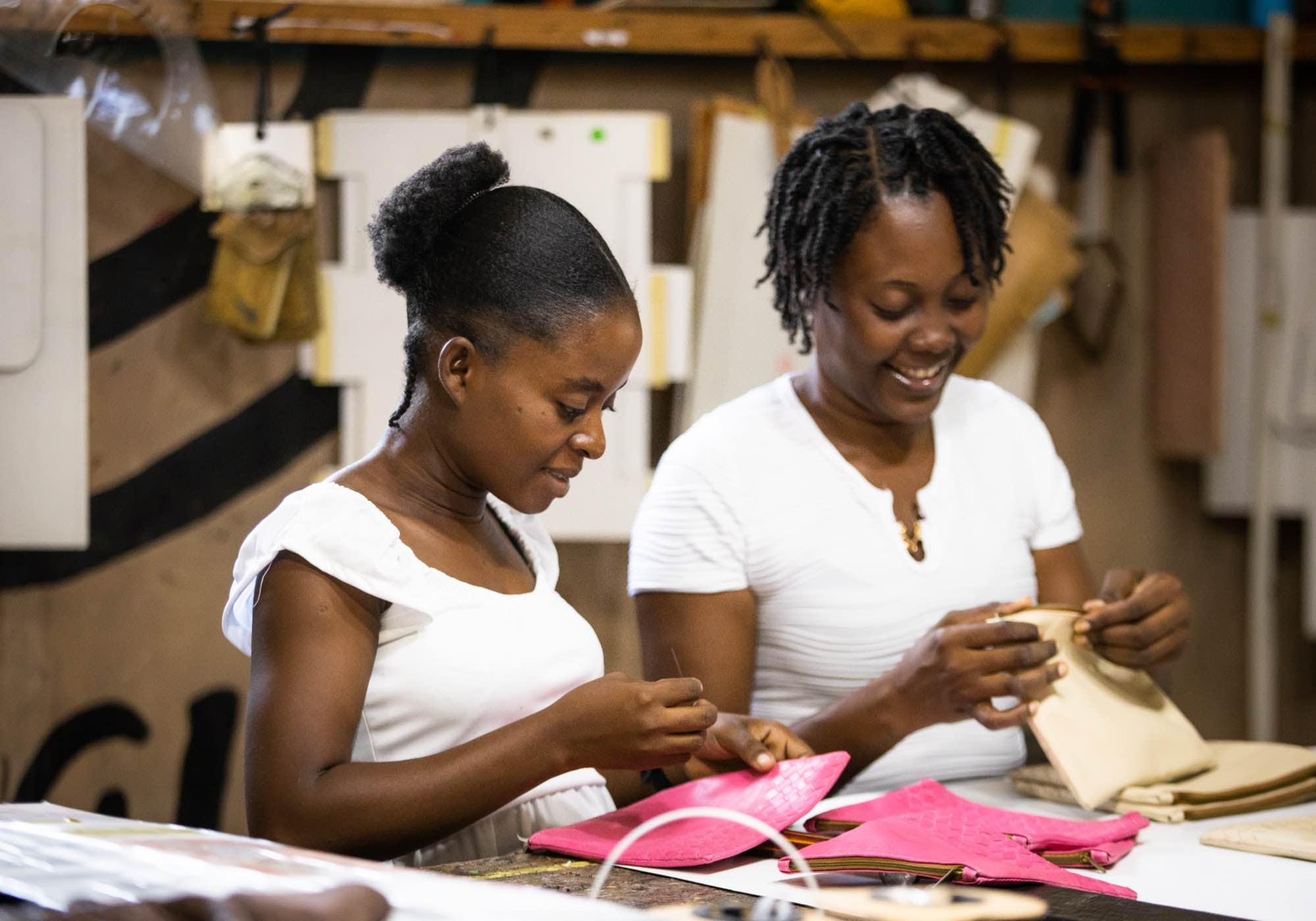 Two women crafting leather pouches and accessories