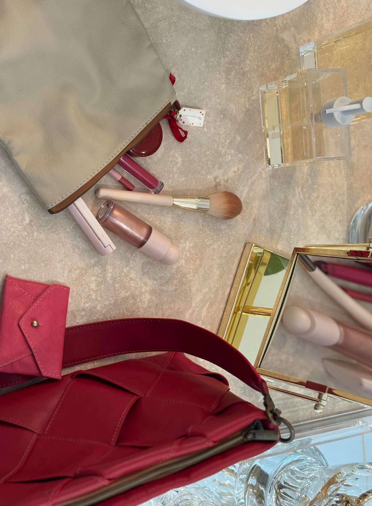 Makeup bag and a red handbag in a bathroom