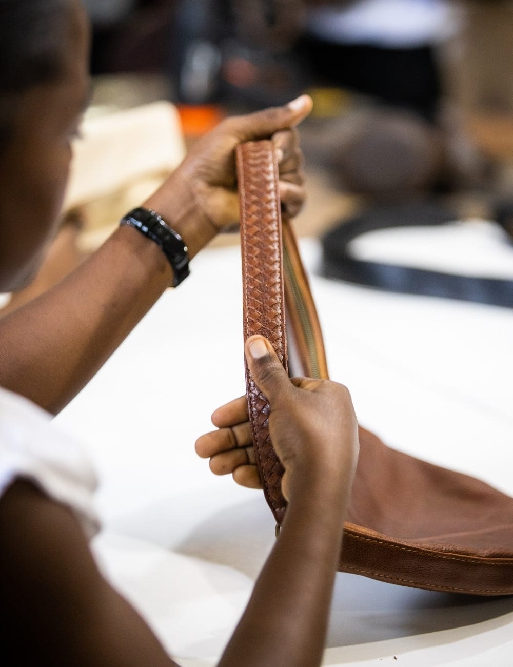 Artisan working on a brown leather bag with intricate stitching