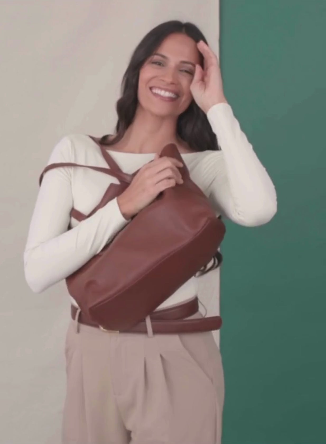 The mid tote in mahogany from the spring collection held by model showcasing the bag in a video.