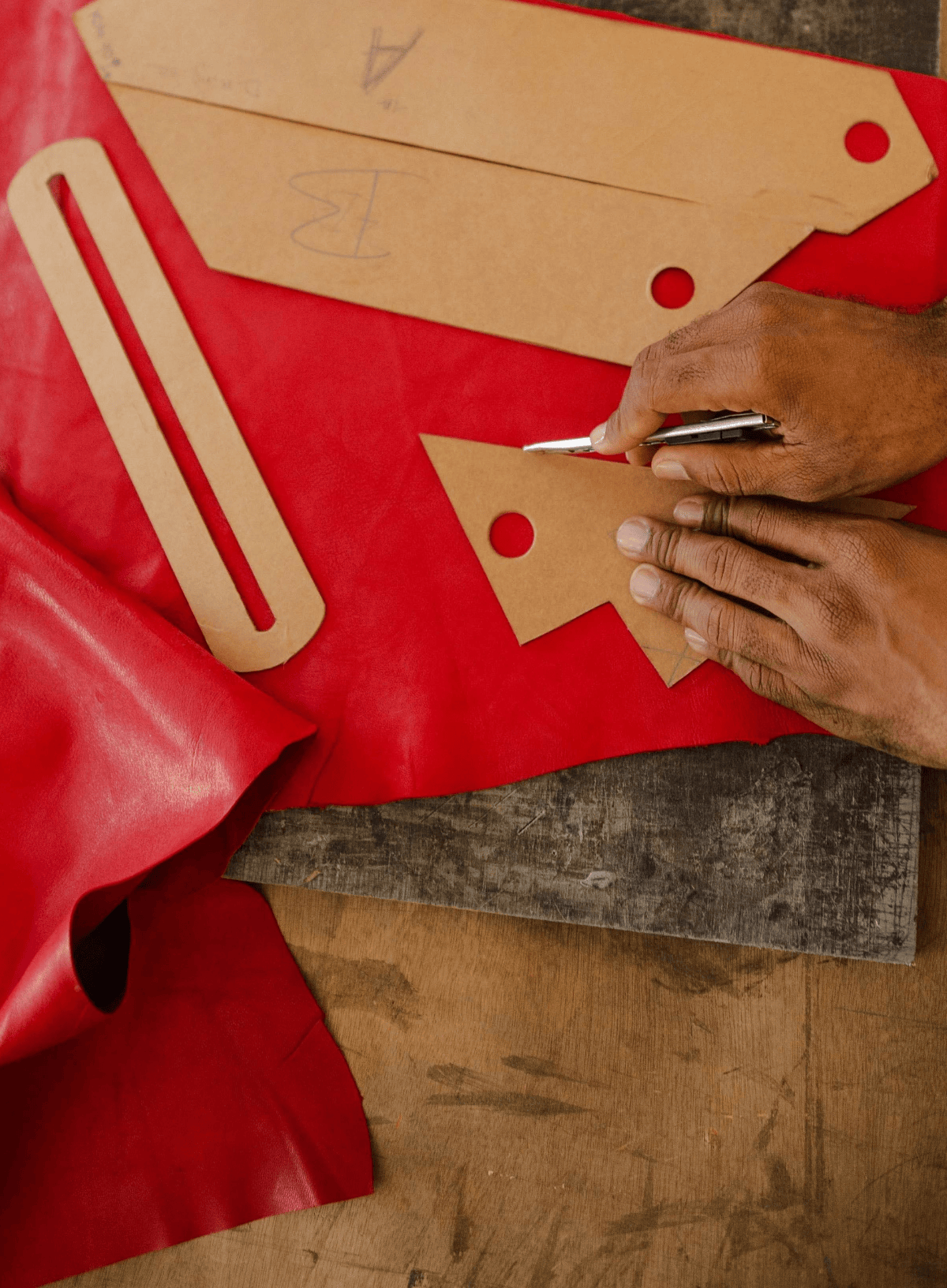Person working with red leather pieces on a work surface
