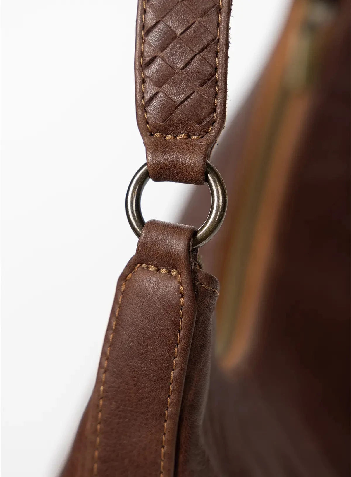 Close-up of a brown leather bag with a woven strap on a white background