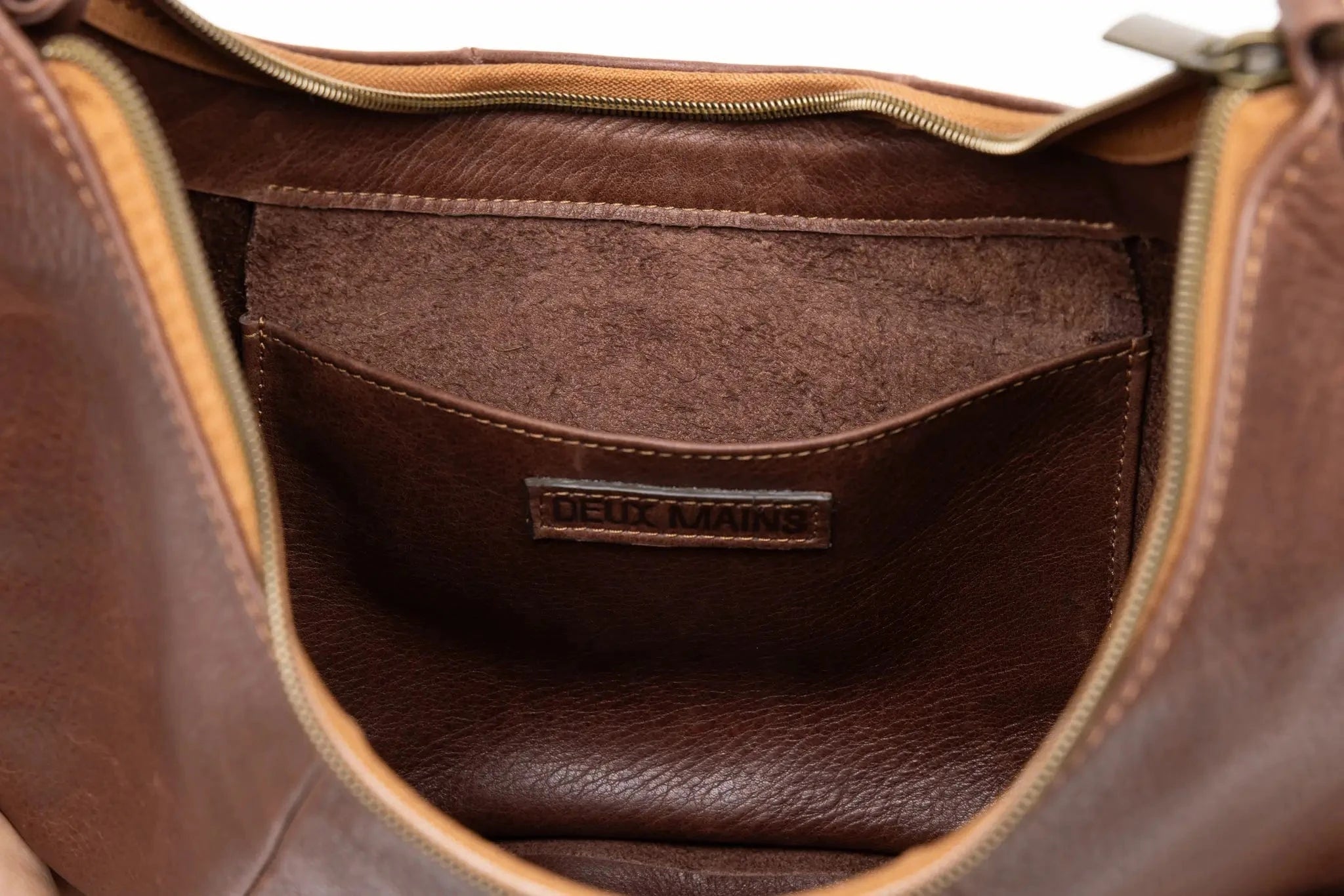 Close-up of a brown leather bag with visible stitching and brand name.