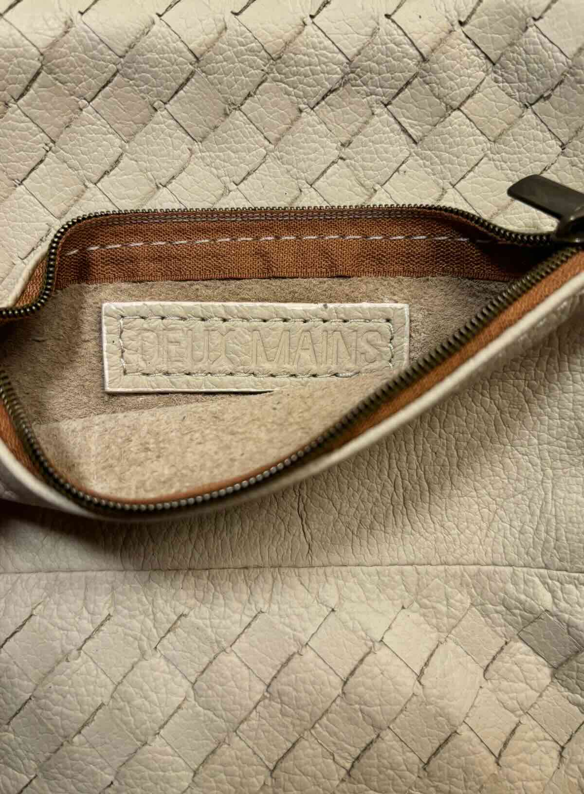 Close-up of a beige woven leather pouch with a visible brand label