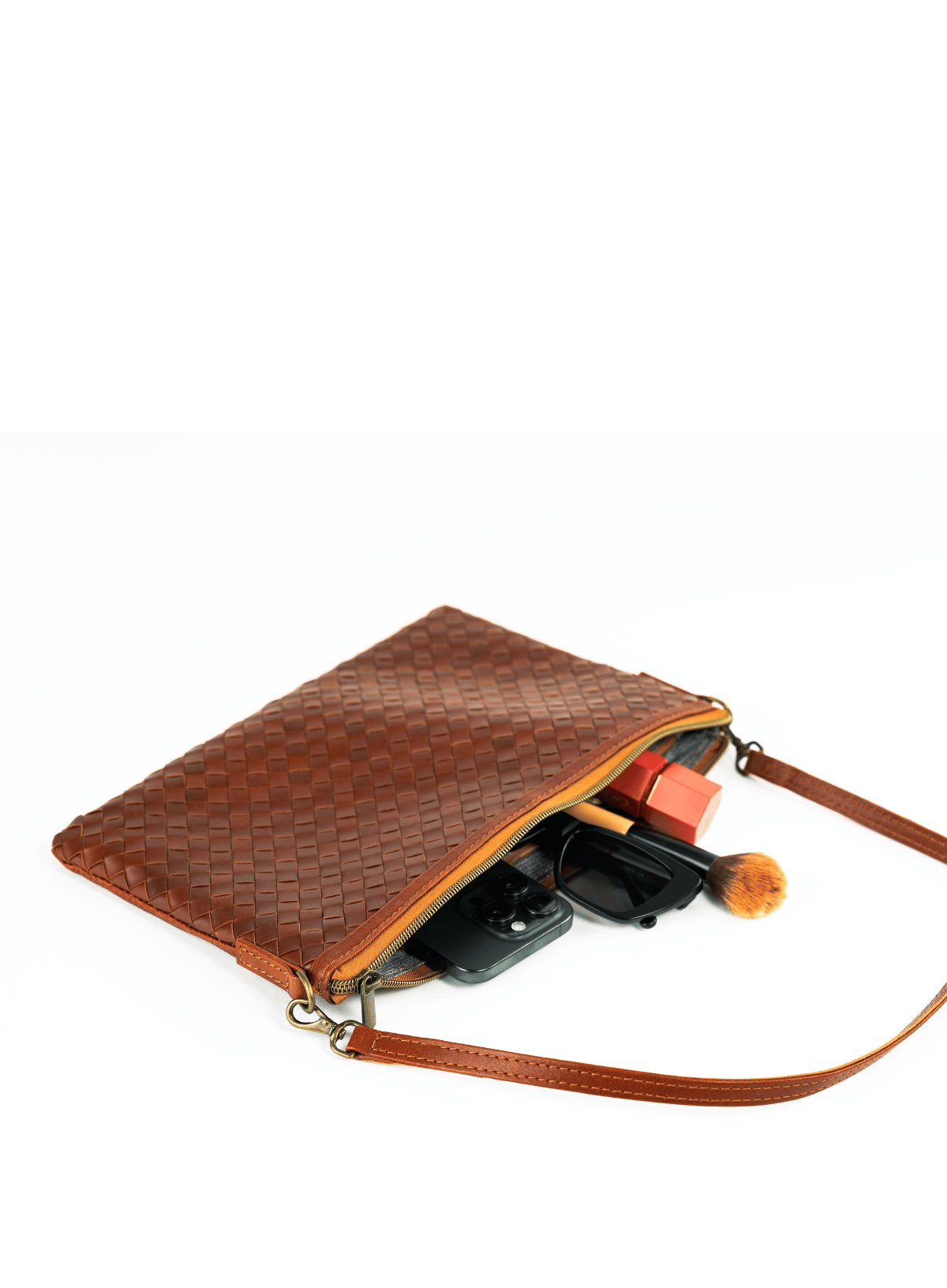 Brown woven clutch bag with a strap on a white background
