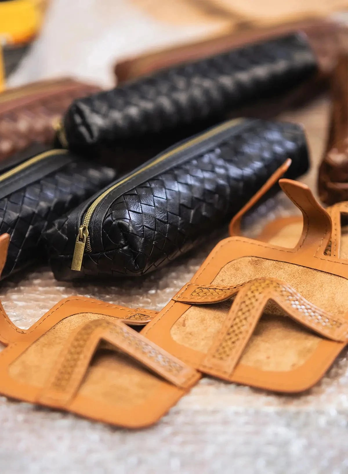 Close-up of leather products including a black woven pencil cases and coasters in factory