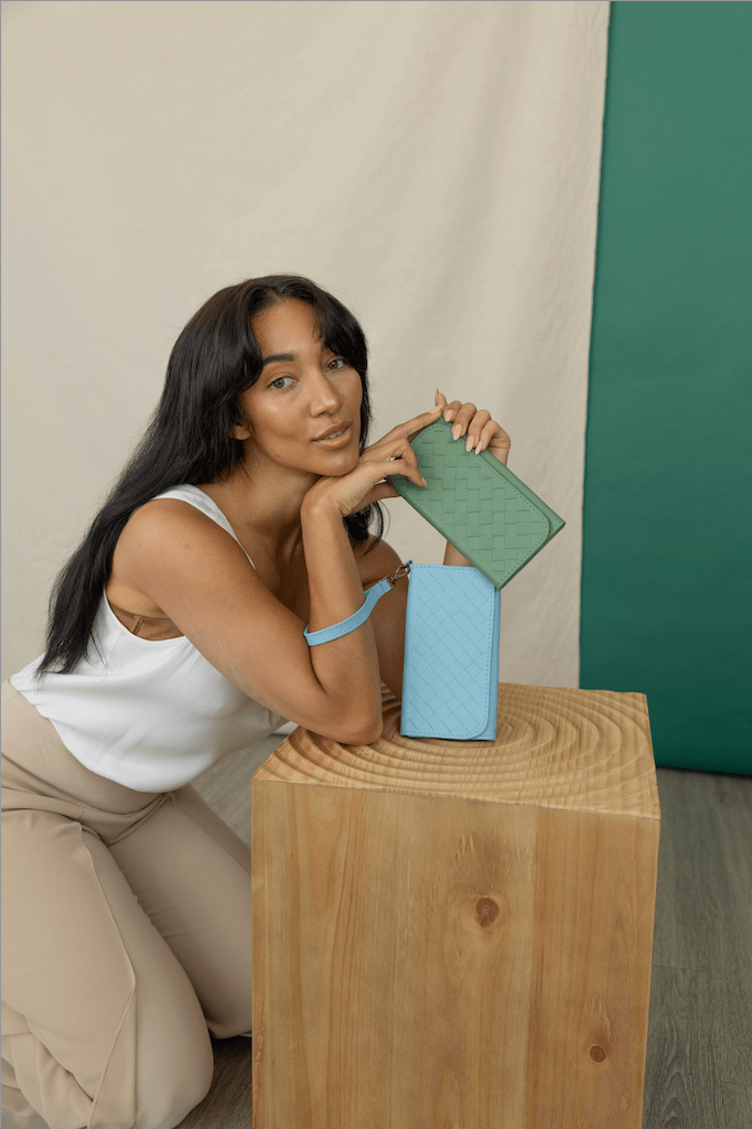Woman holding a green and blue wallets against a beige and green background