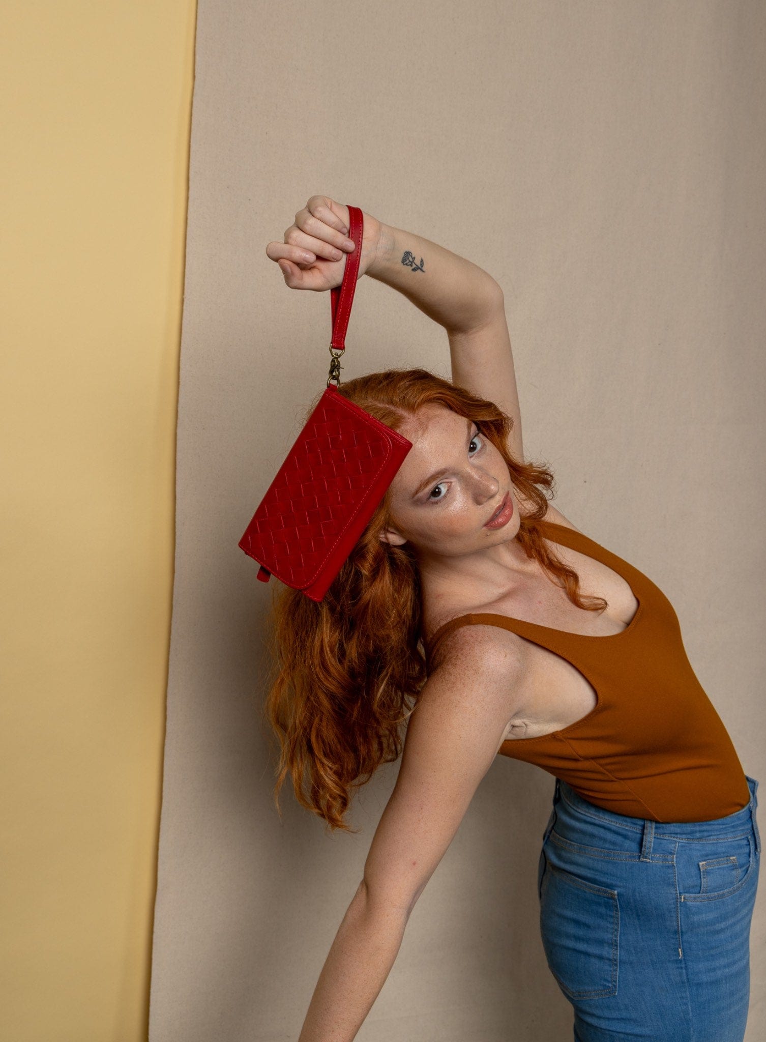 woven wristlet wallet from ethically crafted accessories in red held by model showcasing front view.