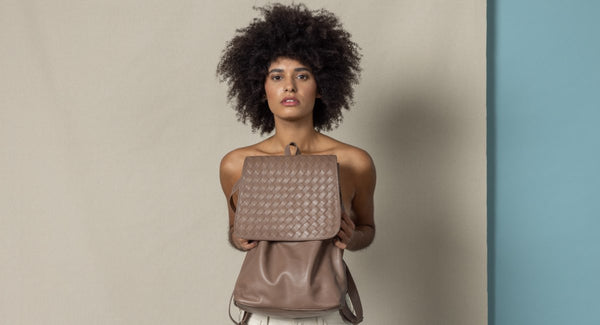 blog banner of a model holding a backpack in front of her for the spring collection.