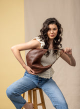 baguette bag from womens bags in brown held by model showcasing front view.