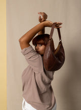 baguette bag from womens bags in brown held by model showcasing side view.