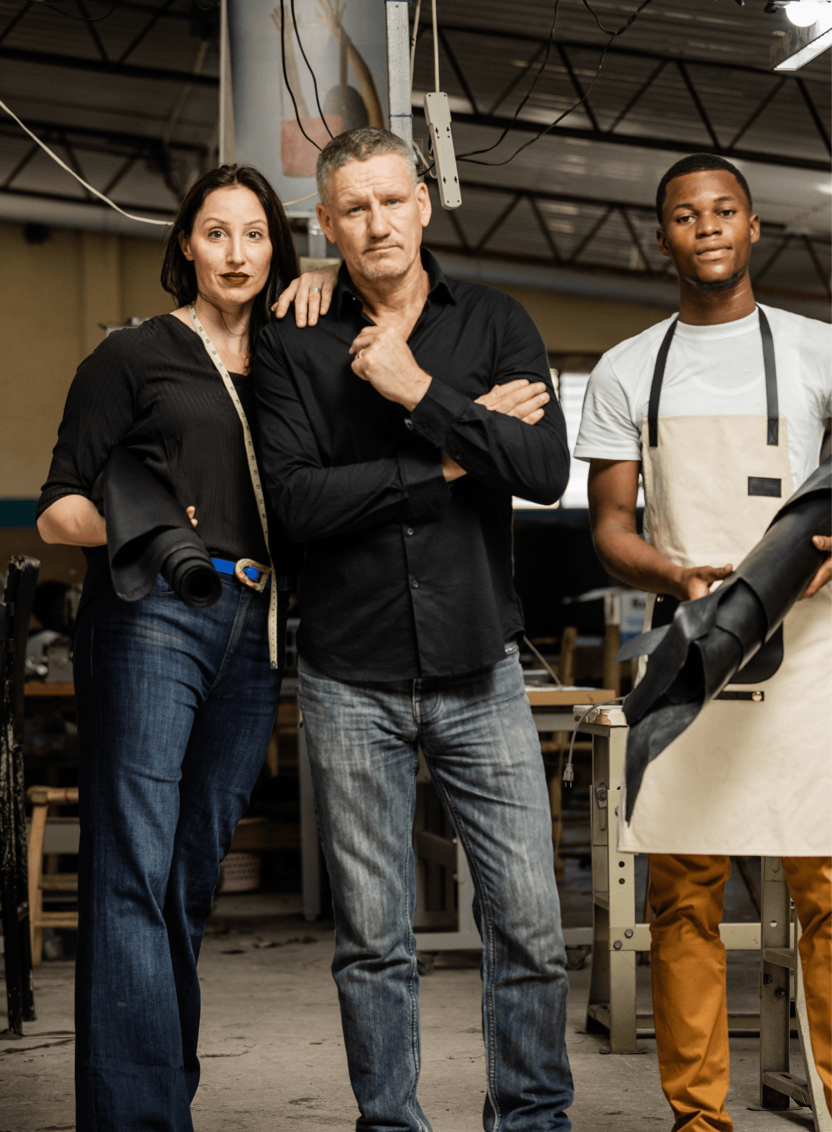 Three people standing together in a workshop setting holding full grain leather