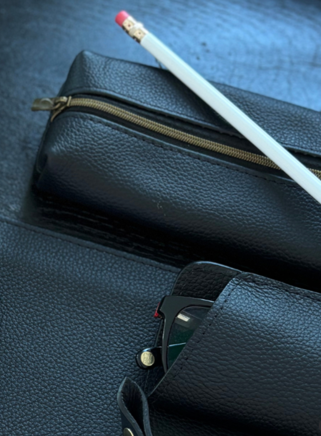 Black leather pencil case with pencil and glasses