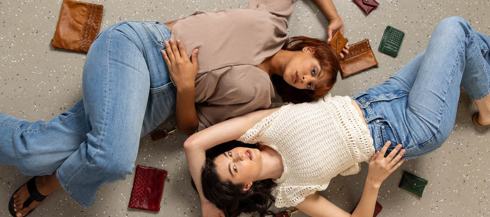 two models lying on the floor surrounded by a collection of autumn accessories, showcasing sustainable seasonal fashion trends and styles.