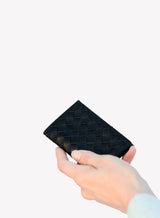  handwoven leather card holder in black with a close-up showcasing details by model.