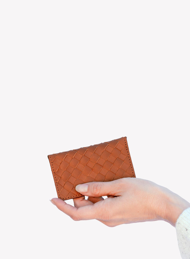 handwoven leather card holder in orange with a close-up showcasing details by model.