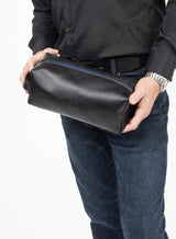 iron tight toiletry bag in black showcasing blue stitching and model holding washbag.