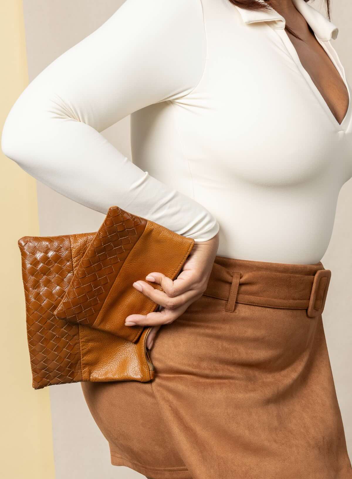 large pouch from ethically crafted accessories in cognac held by model showcasing front view.