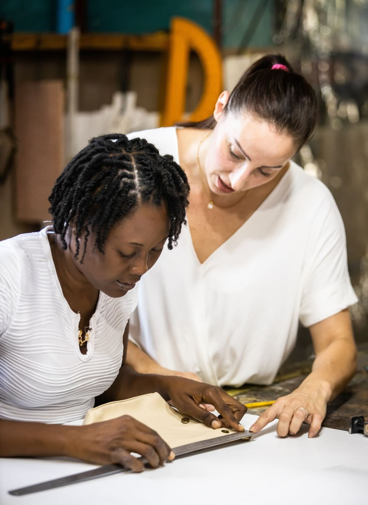 haitian artisan handcrafting and measuring make up bag in bone in haiti factory.