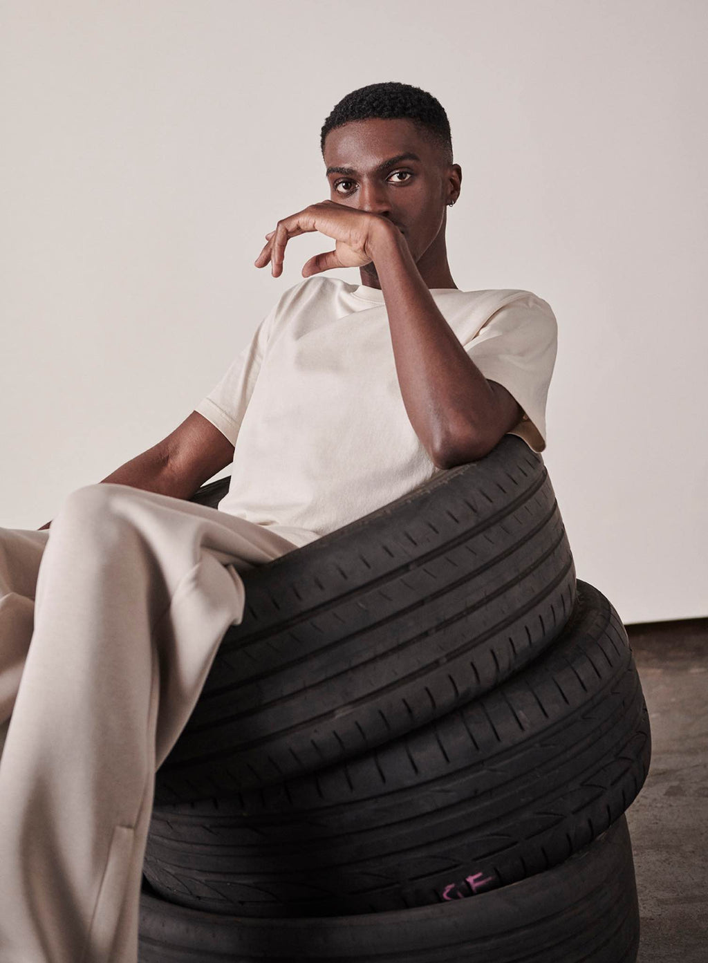 Men's criss cross leather sandals in cognac held by male model and made with recycled and responsibly sourced materials.