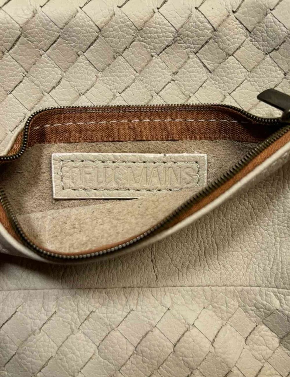 Close-up of a beige leather pouch with a visible brand label.