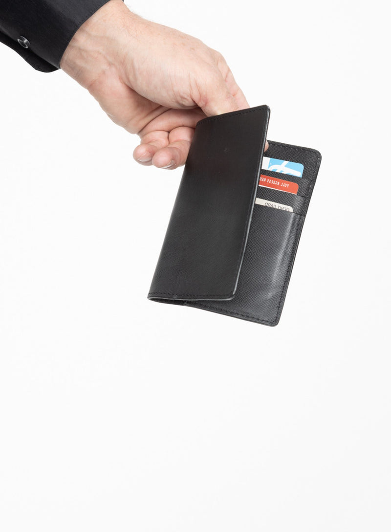 operators passport cover in black showcased by model holding it open with cards in it.