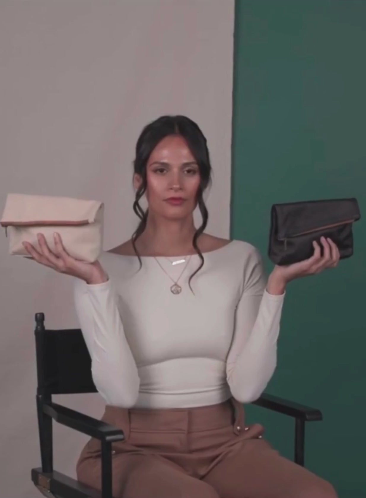 Makeup bag in bone and black held by model throwing them up into the air.