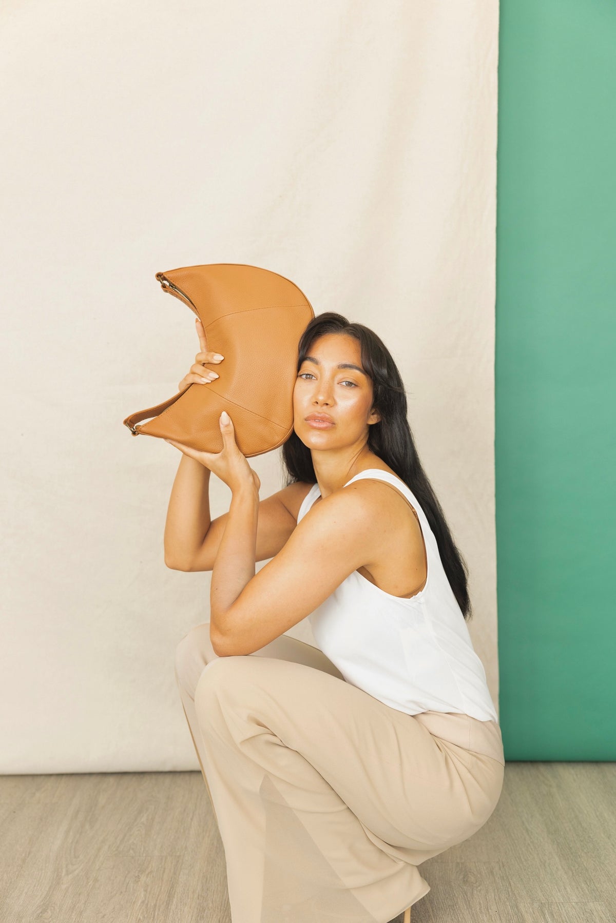saddle shoulder bag mahogany spring collection held by model.