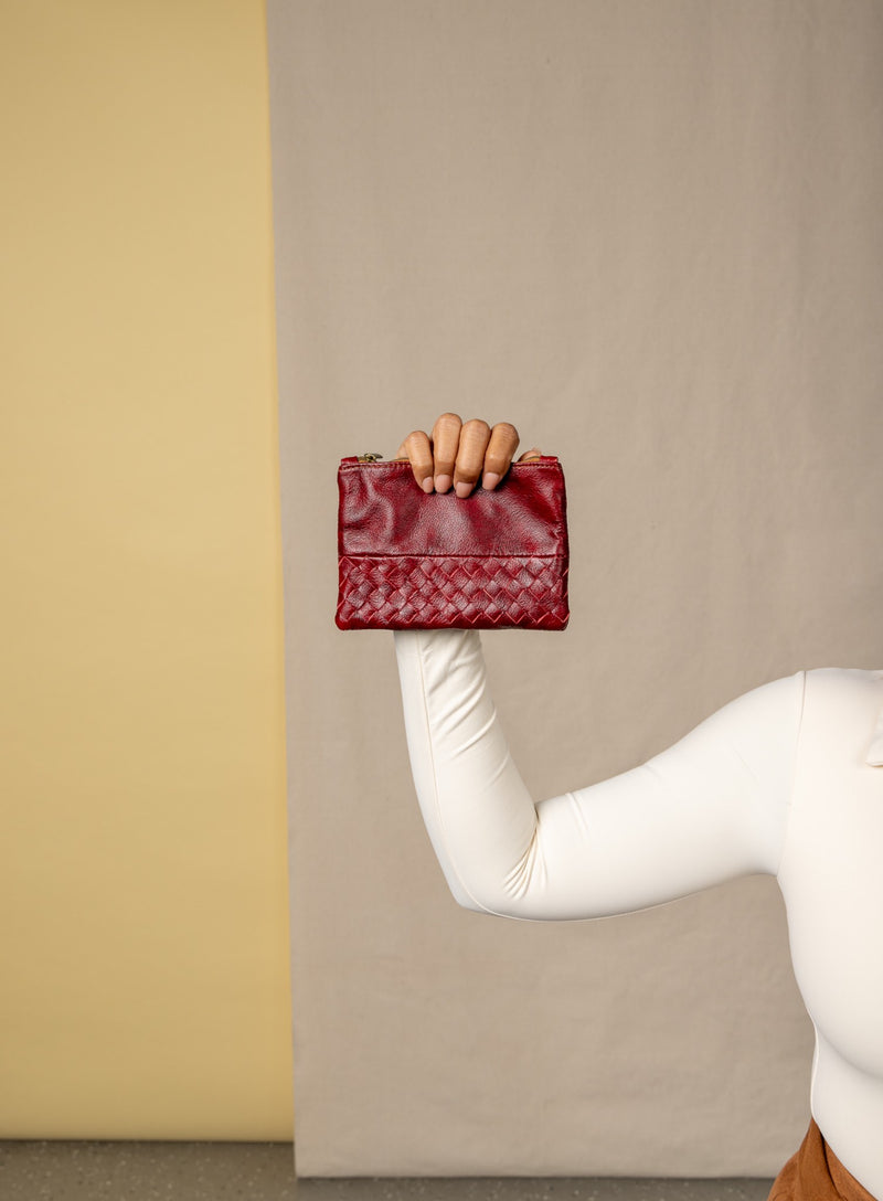 small pouch from ethically crafted accessories in bordeaux held by model showcasing front view.
