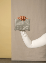 smalll pouch from sustainably hand made accessories in bone held by model showcasing front view.
