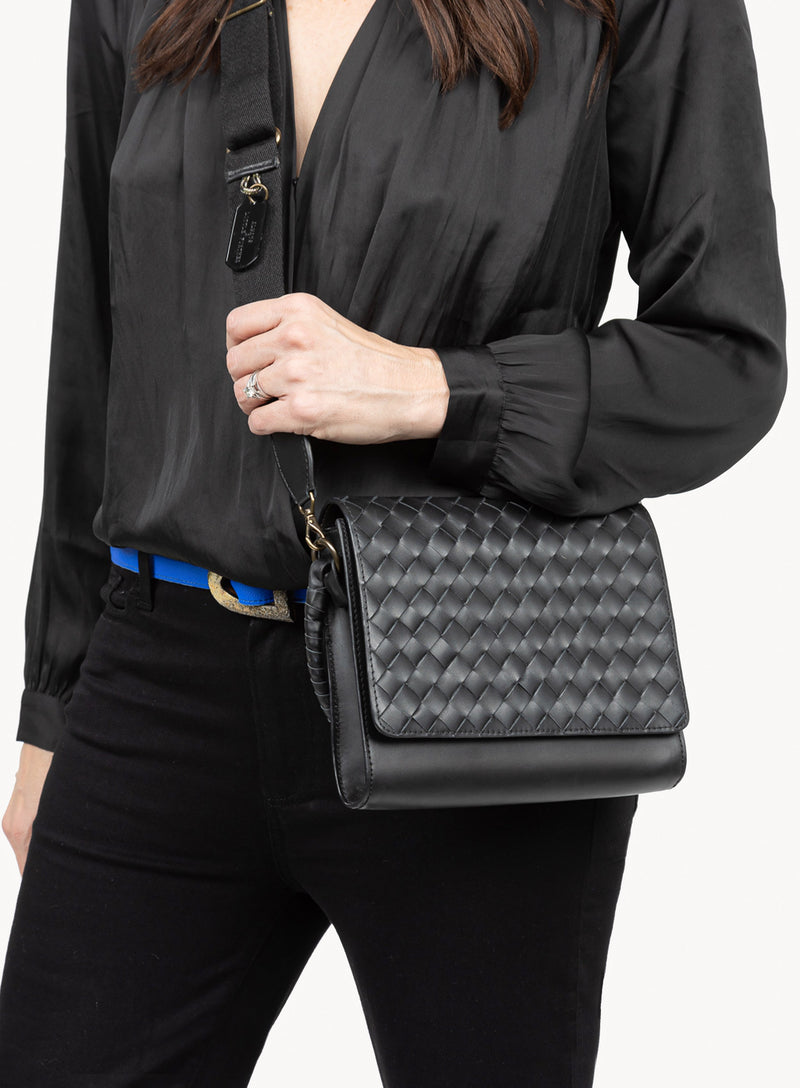 the colonel crossbody in black showcasing side-view of model holding the handbag and bag details.