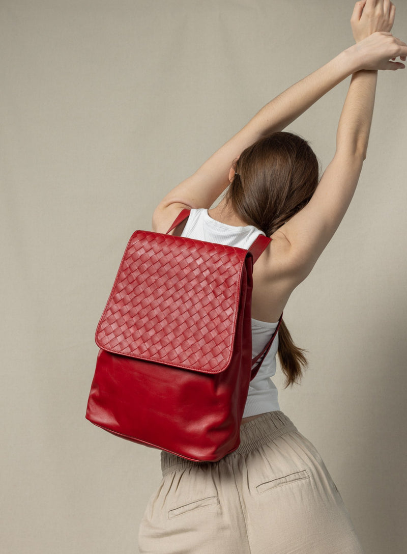 woven backpack in red from womens bags collection showcased by model turned around and wearing it and stretching.