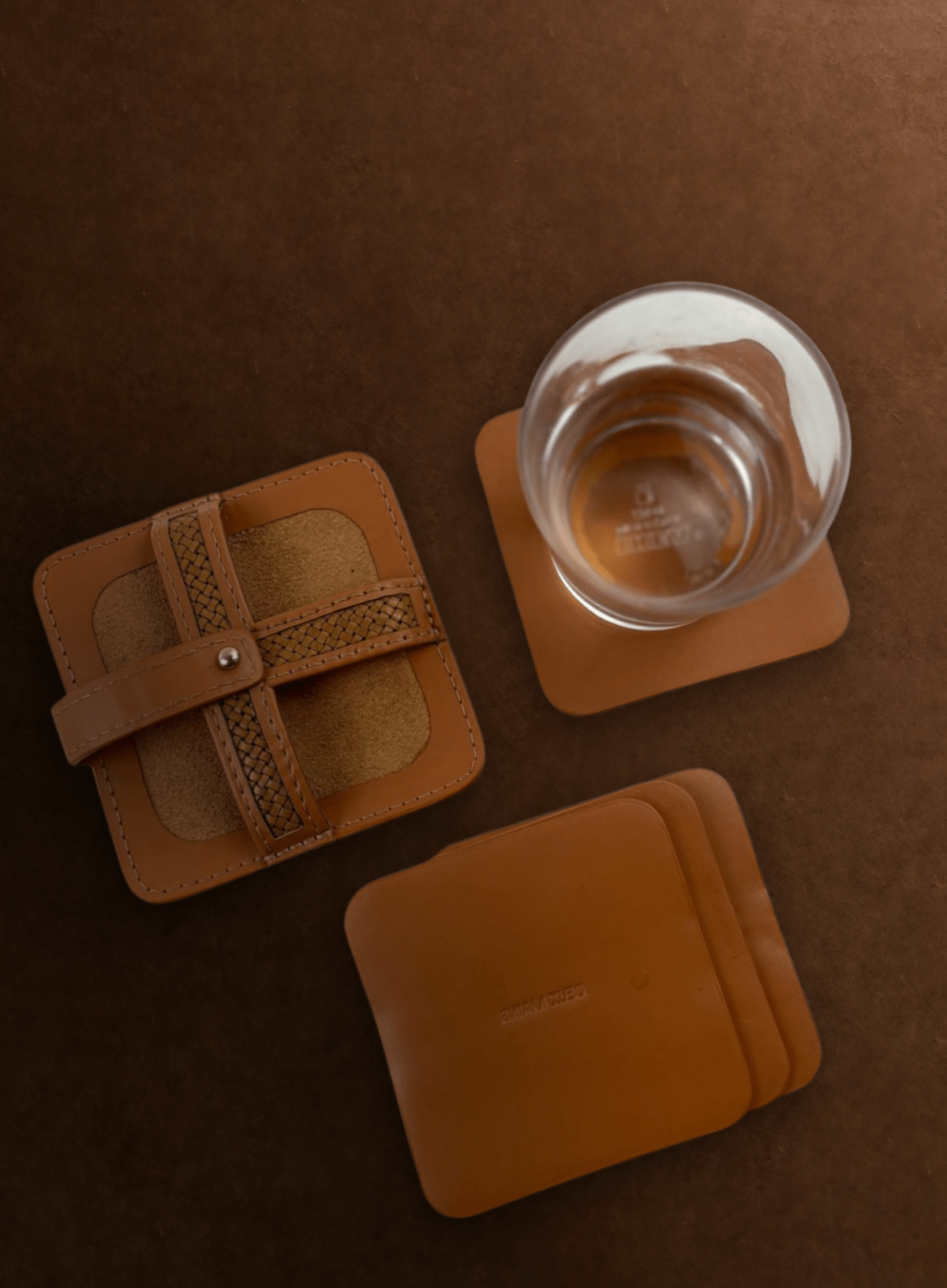 Cognac woven leather coasters with glass flat lay