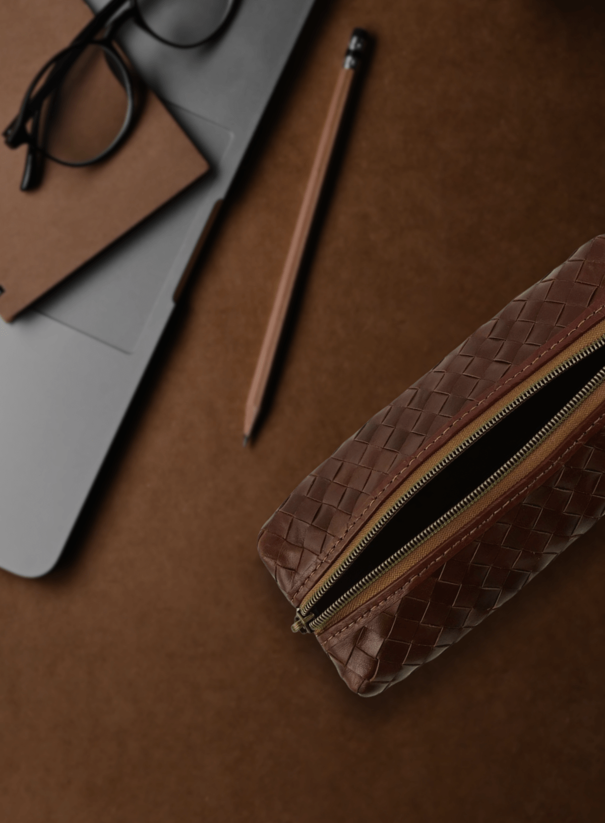 Black woven pencil case with laptop and supplies flat lay.