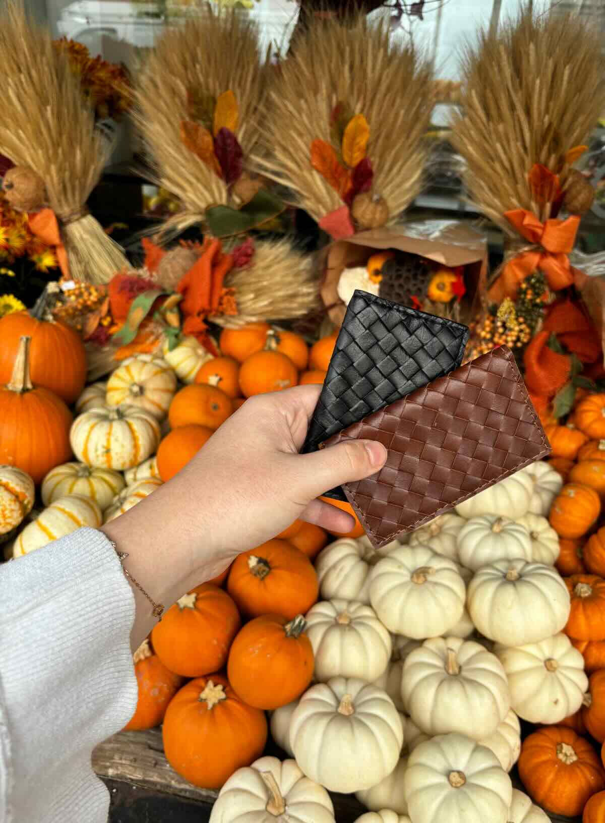 woven wallet from our leather accessories in the new fall collection showcased in front of pumpkin stand.